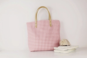 Detail of pink gingham canvas tote bag with leather handles and gold rivet accents