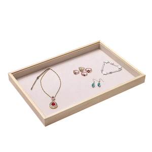 Top view of wooden jewelry display tray with beige velvet lining for rings and necklaces