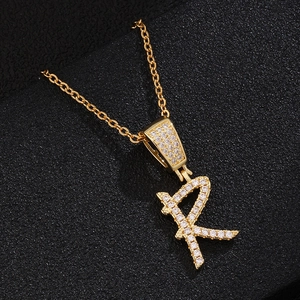 Detailed close-up of a golden R-shaped letter pendant with sparkling zircon micro-paving