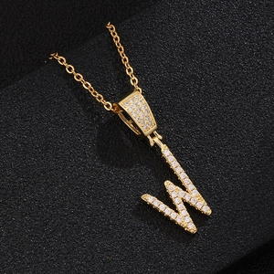 Macro view of gold pendant necklace with letter W inlaid with white zircon crystals