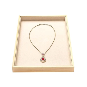 Detailed macro view of a gold waterdrop ruby pendant displayed in a wooden jewelry tray