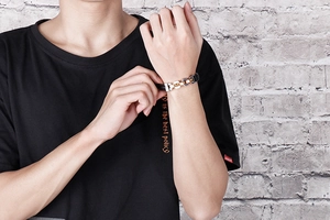 Close-up of a woven black leather bracelet with gold and silver metal accents on a wrist
