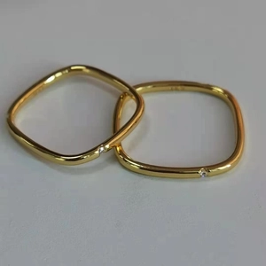 Close-up of two gold titanium square rings with sparkling round zircon stone accents