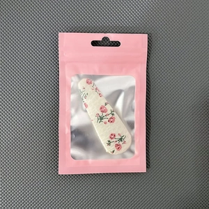 Pink matte packaging bag with transparent window showing floral hair clip inside