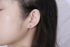 Macro detail of diamond-shaped gold titanium stud earrings with blue enamel inlay