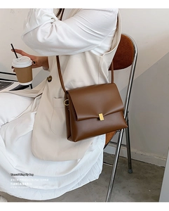 Dettaglio di una borsa a tracolla vintage in pelle marrone scuro con fibbia dorata