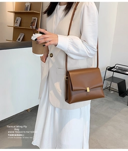 Dettaglio di una borsa a tracolla in pelle marrone con elegante chiusura quadrata dorata