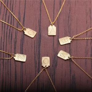 Creative gold square letter pendants on copper necklace over dark wood texture