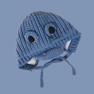 Close-up of blue knitted dinosaur baby hat with cartoon eyes and warm ear flaps