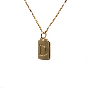 Close-up of gold plated copper rectangular pendant featuring an engraved letter D charm