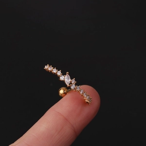 Macro view of gold curved ear stud with clear zircon gems shown on a fingertip