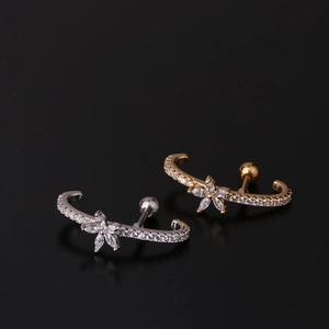 Close-up of gold and silver stainless steel cartilage earrings with zircon floral designs