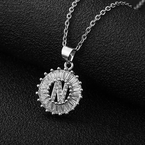 Gros plan du pendentif lettre N en argent avec zircons baguette sur fond noir élégant