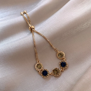 Detail of adjustable gold-plated bracelet with navy blue and champagne crystals on silk