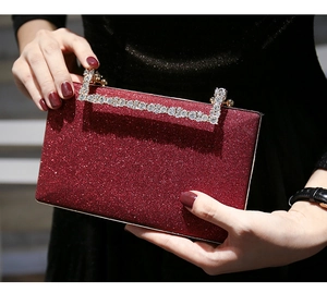 Close-up of red glitter evening clutch with rhinestone handle held by a model
