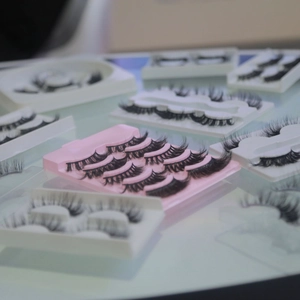 Macro shot of assorted faux mink eyelashes in pink and white storage trays