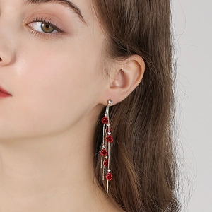 Boucles d'oreilles pampilles dorées avec roses rouges et cristaux sur modèle