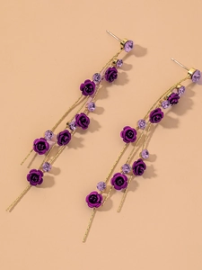 Détail de boucles d'oreilles longues à pampilles rose violette avec strass et chaînes dorées
