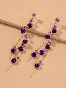 Détail de boucles d'oreilles pendantes avec fleurs violettes et chaînes dorées