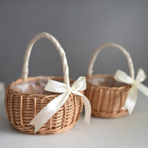 Handwoven wicker flower girl baskets with white ribbon handles and satin bows for wedding decor