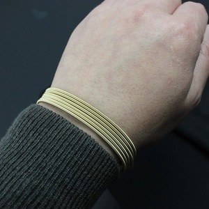 Detailed view of multilayer gold wire coil bracelet worn on wrist for sizing
