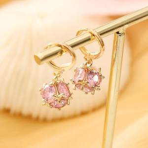 Detail of pink crystal earrings in a gold cage setting displayed on a metal stand