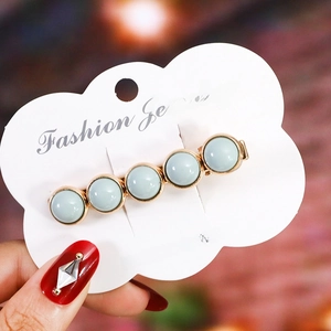 Detailed macro view of mint blue beaded hair clip on a white fashion jewelry card