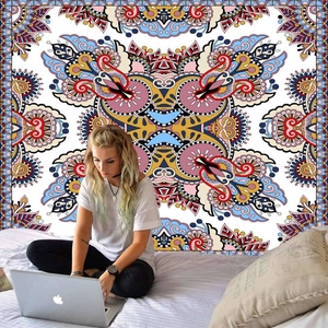 Ethnic mandala tapestry with colorful paisley patterns behind woman on bed using laptop