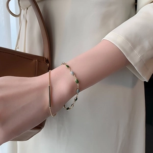 Ensemble de bracelets dorés avec pierres vertes et bleues porté par un mannequin