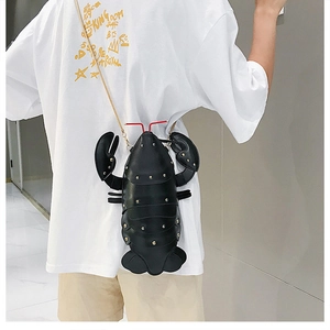 Detail of cute lobster-shaped black crossbody bag with gold studs and chain strap