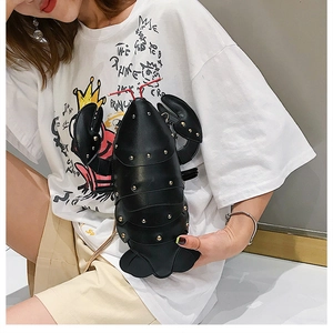 Close-up of a black lobster-shaped crossbody bag with gold studs and chain strap
