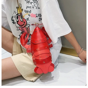 Close-up of a creative red lobster shaped crossbody bag with gold chain strap on model