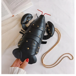 Detail of creative black lobster crossbody bag with gold rivets and metallic chain strap
