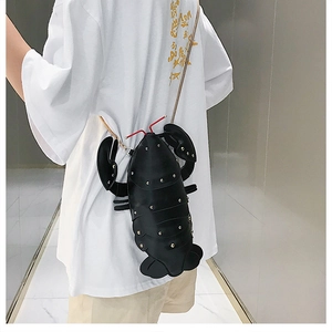 Detail view of a black lobster-shaped crossbody bag with gold studs and metal chain strap