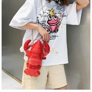 Detail of red lobster-shaped crossbody bag featuring silver rivets and metal chain strap