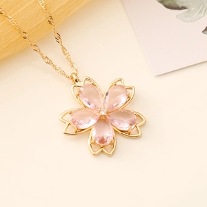 Macro shot of gold cherry blossom necklace featuring pink crystal petals and a center gem