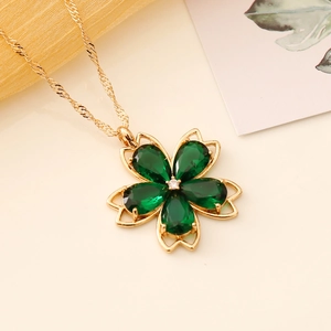 Floral crystal necklace featuring green water-drop stones and a gold chain on a warm base