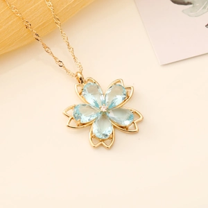 Detailed macro of cherry blossom necklace with light blue gemstones and gold chain