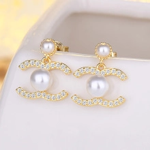 Detailed macro view of gold-tone earrings with sparkling pavé crystals and drop pearls