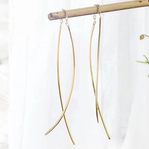 Detail view of long golden S925 sterling silver tassel earrings hanging on white fabric