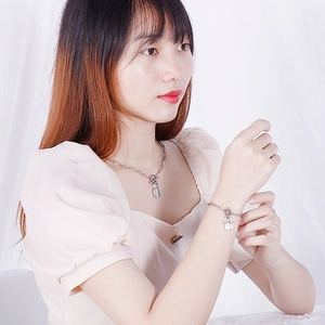 Silver titanium steel padlock pendant necklace and bracelet set shown on a female model