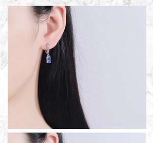 Detailed view of silver hoop earrings featuring a rectangular blue crystal and cubic zirconia