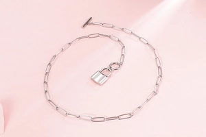 Detailed view of silver paperclip chain necklace with padlock pendant and OT buckle