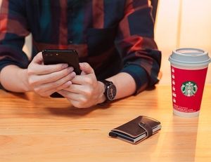 Close-up of brown leather card holder with metal frame and stitching on a wood table