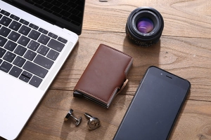 Brown PU leather dual card wallet with metal slider on a professional wood workspace
