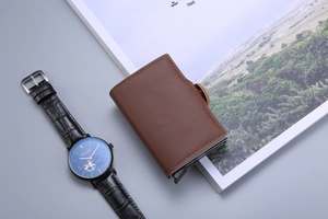 Overhead view of a brown leather card holder with dual aluminum pop-up card slots on a desk