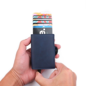 Detailed view of hand-held blue PU leather wallet with automatic pop-up card mechanism
