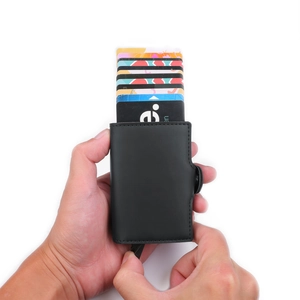 Hand holding a black PU leather card holder showing the automatic pop-up mechanism and cards