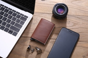 Slim RFID blocking wallet in brown leather on a wooden desk with business accessories