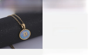Detail of 18K gold stainless steel pendant with letter B on blue sea shell inlay